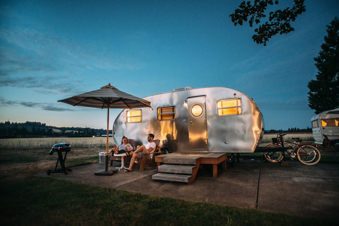 man-and-woman-sitting-in-front-of-rv-trailer-tcgassd5g04
