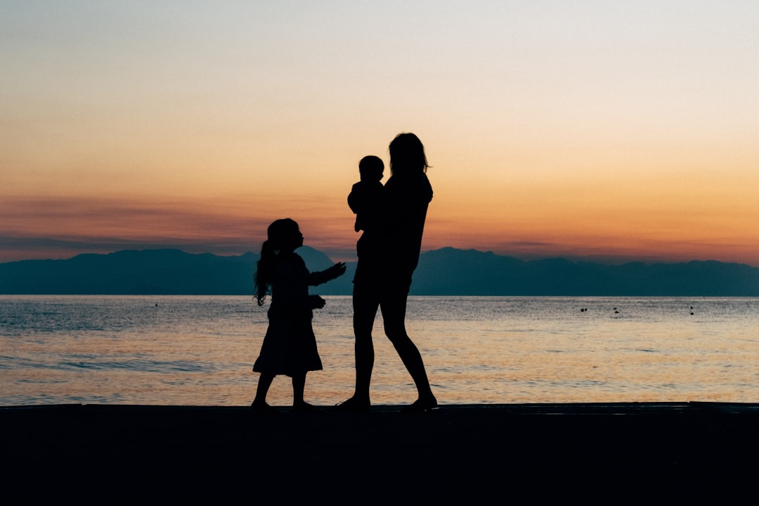 A family of three. Brother, sister and mother, stroll on the beach in Greece at sunrise. When the kids cant sleep on holiday, take them for a walk on the beach. If you can wake up it makes great photos for the golden hour.